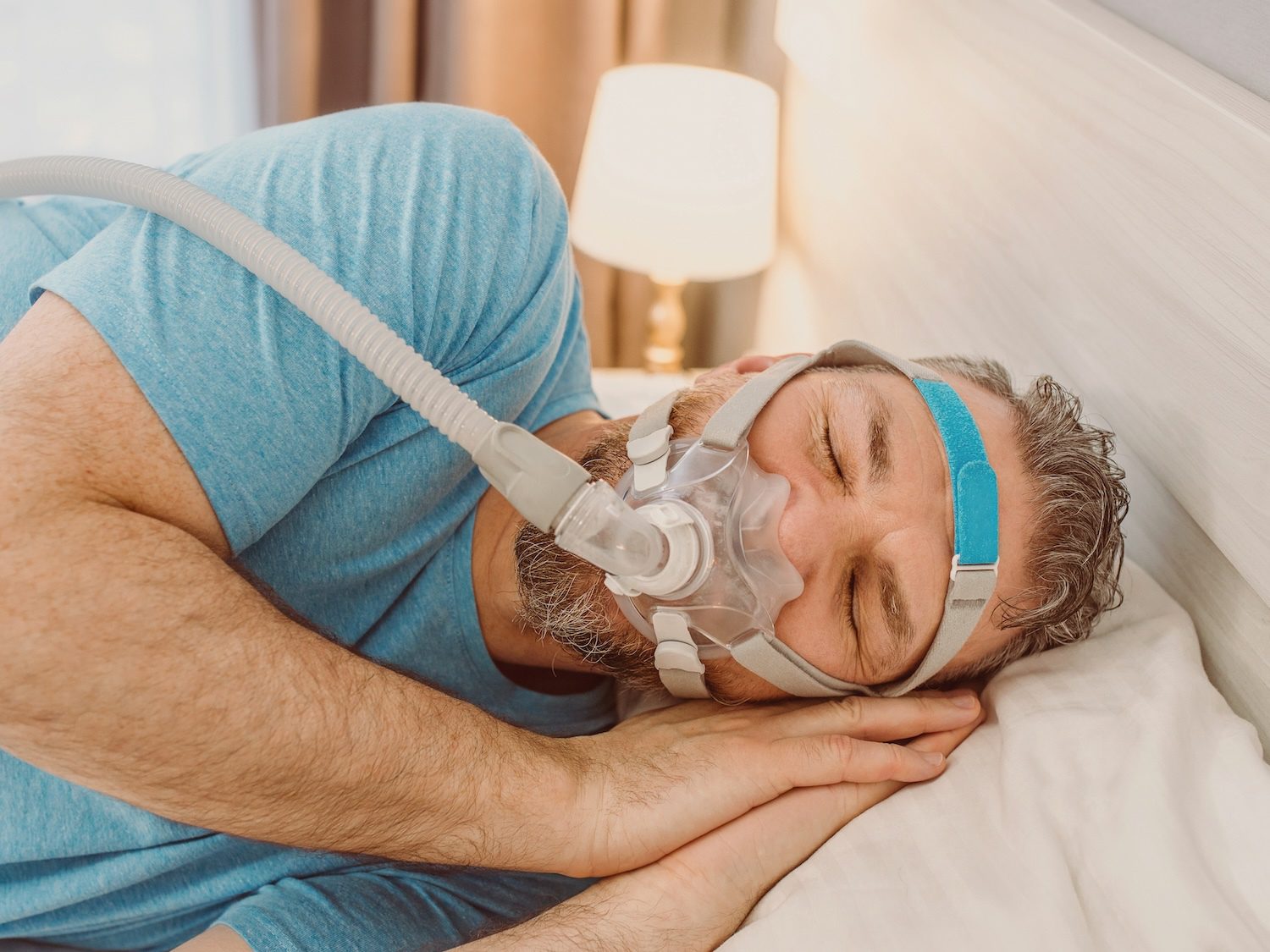 Sleeping man with chronic breathing issues using cpap machine bed